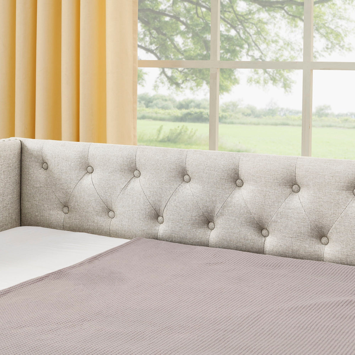 Upholstered daybed in gray fabric with diamond-tufted back and button details on Tampa Home & Garden Store