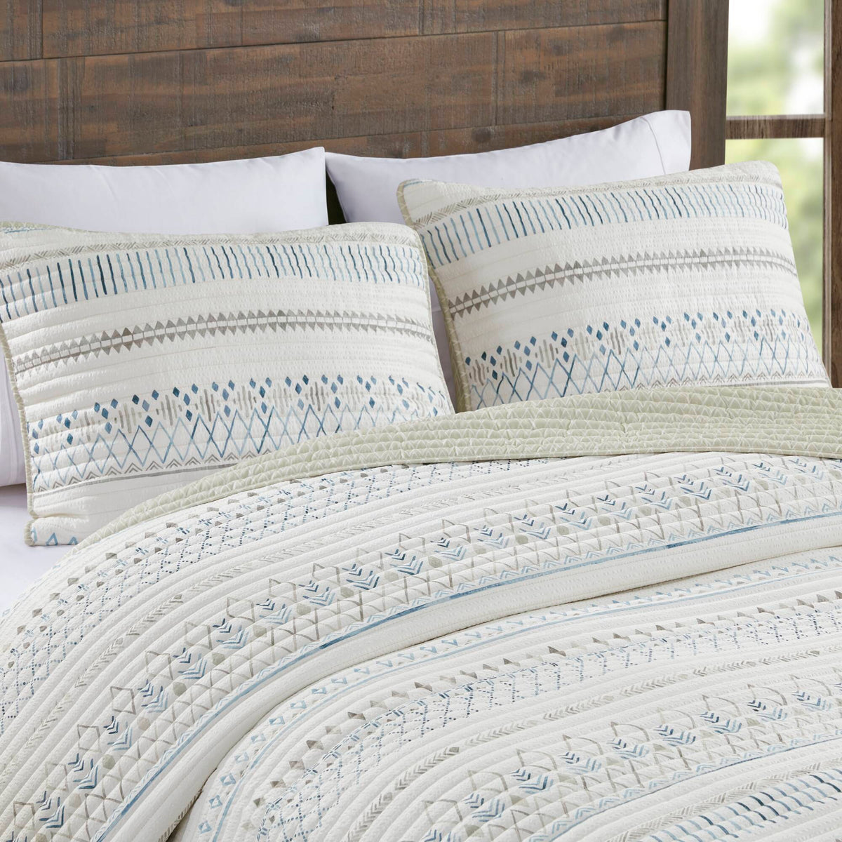 Printed microfiber seersucker quilt set taupe blue reversible design on bed with white pillows on Tampa Home & Garden Store