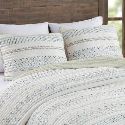 Printed microfiber seersucker quilt set taupe blue reversible design on bed with white pillows on Tampa Home & Garden Store