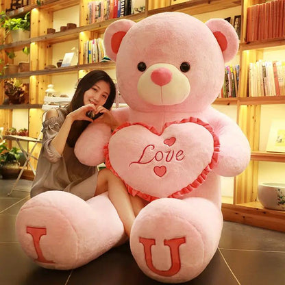 Pink hug bear plush holding a heart-shaped pillow embroidered with Love; large pink teddy on Tampa Home & Garden Store