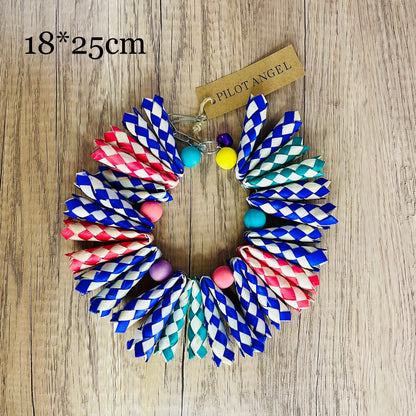 Parrot woodskin hand-woven toy circle with blue red teal braids and beads on wood background on Tampa Home & Garden Store