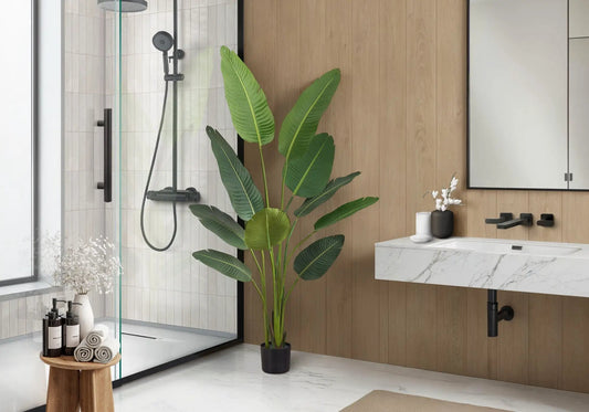 Bird of Paradise artificial plant in a black pot beside a marble bathroom vanity on Tampa Home & Garden Store