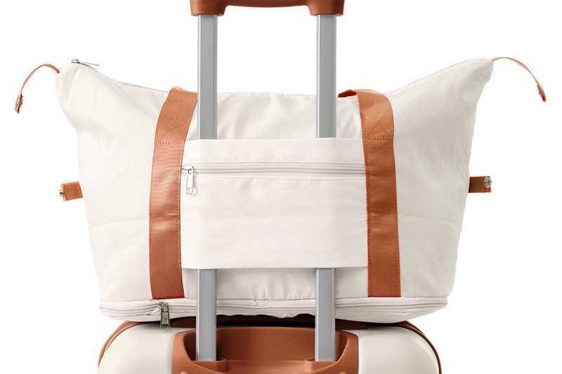 Luggage set with cream tote secured by tan luggage strap atop a white spinner suitcase on Tampa Home & Garden Store
