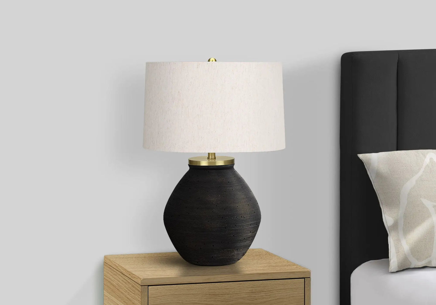 Table lamp with black textured ceramic base and cream shade on a wooden nightstand on Tampa Home & Garden Store