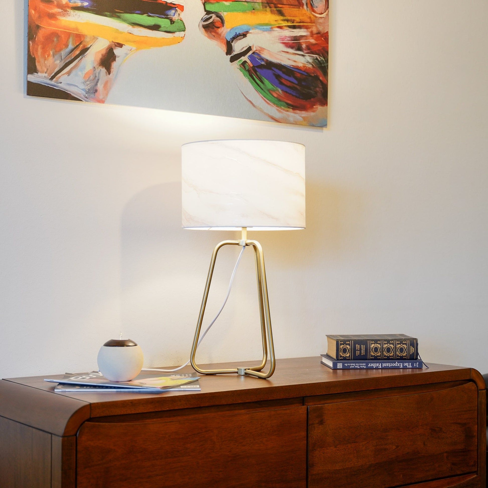 Optima desk lamp with white shade and gold tripod base on a wooden desk on Tampa Home & Garden Store
