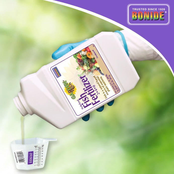 Bonide Fish Emulsion 2-4-0 fertilizer bottle, white plastic with label held by blue glove on Tampa Home & Garden Store