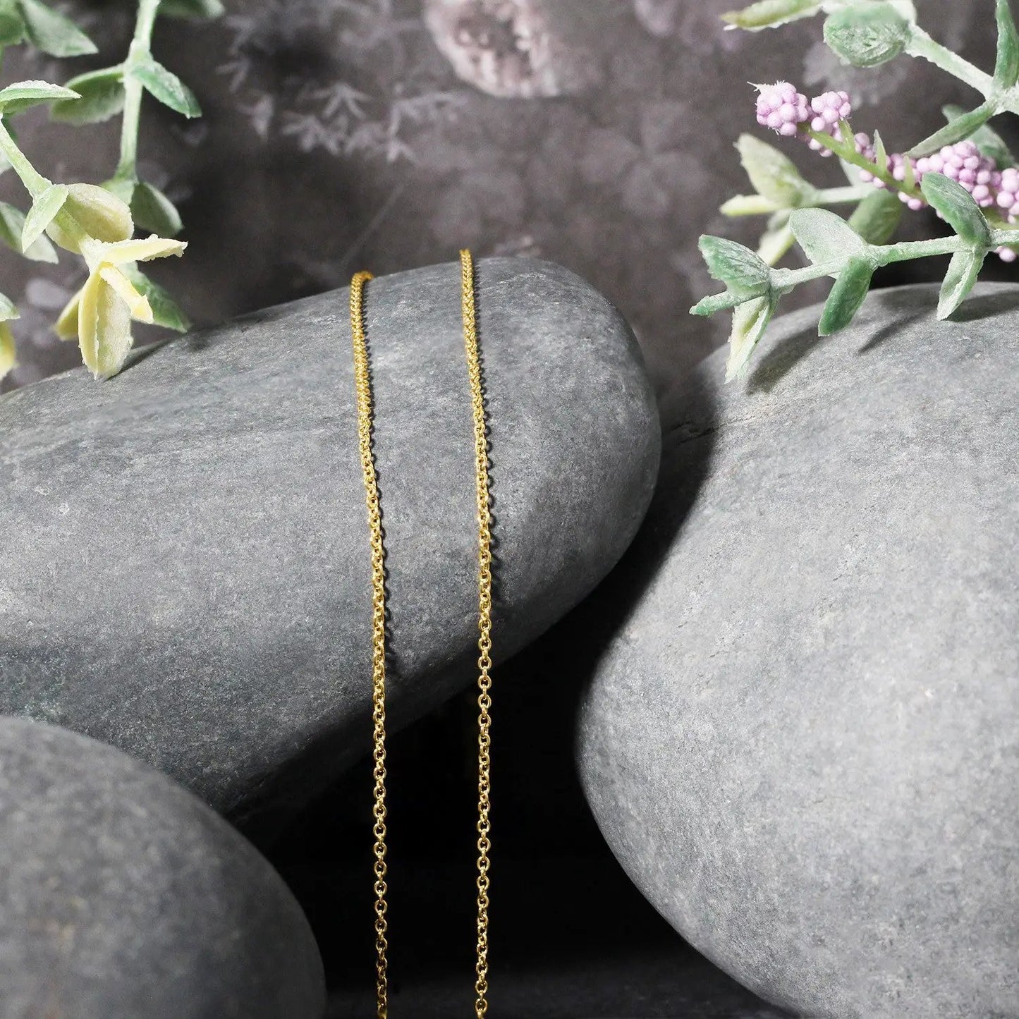 14k yellow gold round cable link chain 1.2mm necklace draped over gray rocks with plants on Tampa Home & Garden Store