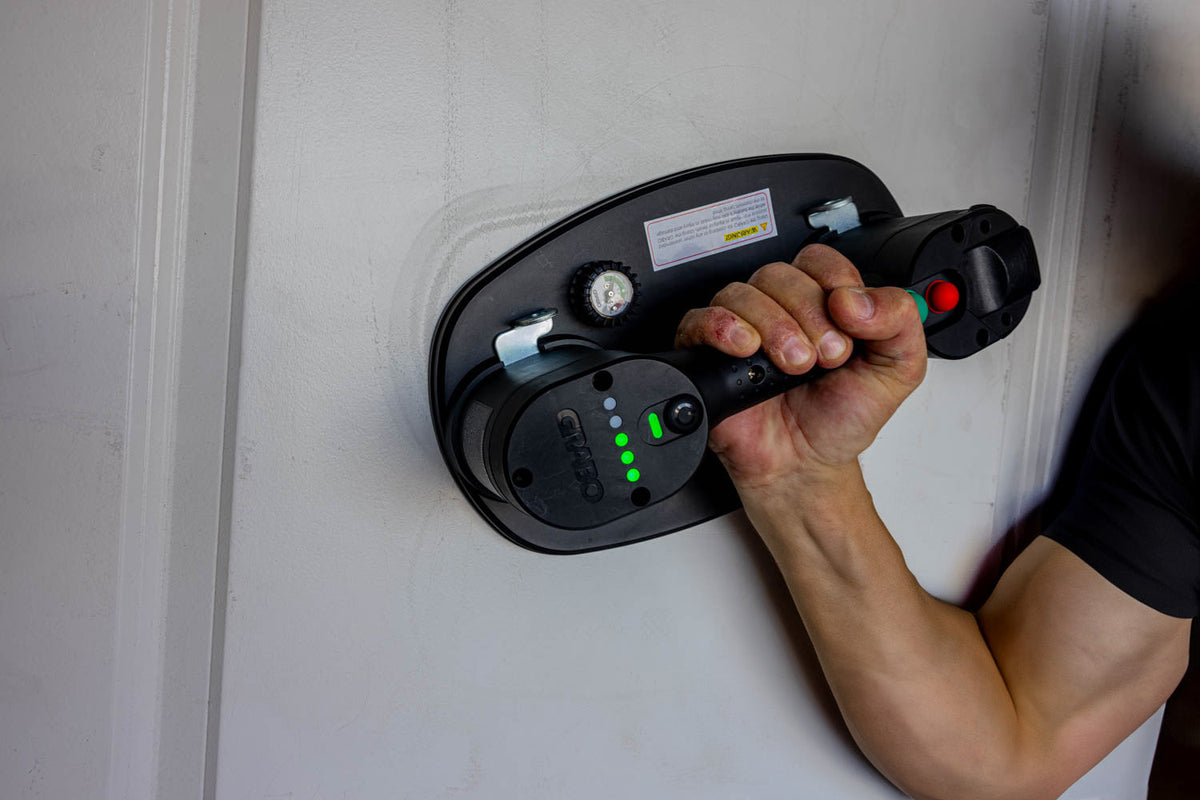 GRABO V2 cordless suction gripster with green LED indicators held by hand on wall on Tampa Home & Garden Store