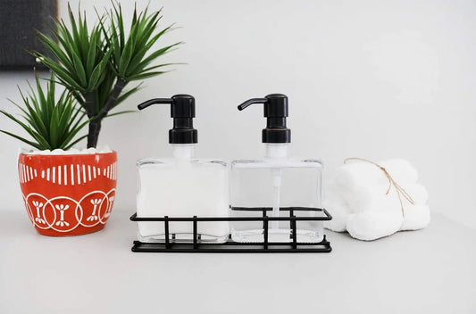 Set of 2 refillable glass soap dispensers with black pumps in a black metal rack on Tampa Home & Garden Store