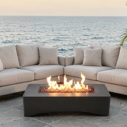 56 inch rectangular propane fire pit table with flames, dark gray base beside beige seating on Tampa Home & Garden Store