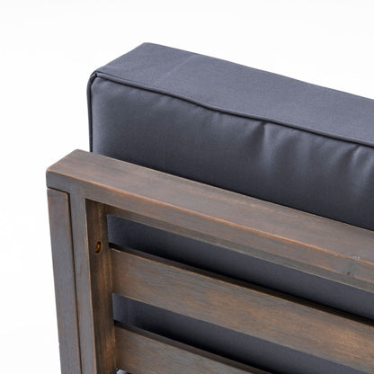 Outdoor acacia wood patio chair with dark gray fabric cushion, close-up of arm and frame on Tampa Home & Garden Store