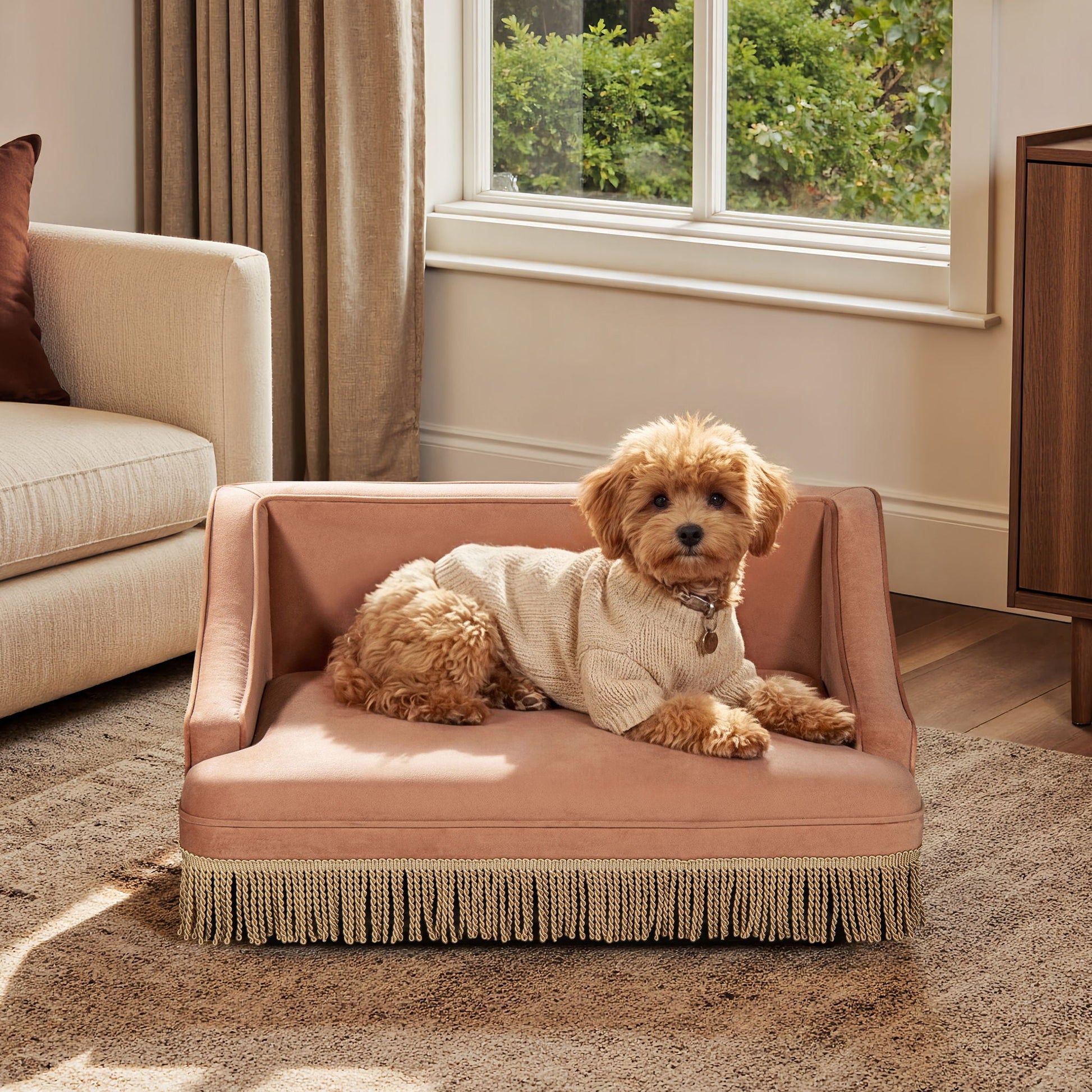 Duchess cat bed sofa in blush pink with fringe trim, placed in living room with two small dogs on Tampa Home & Garden Store