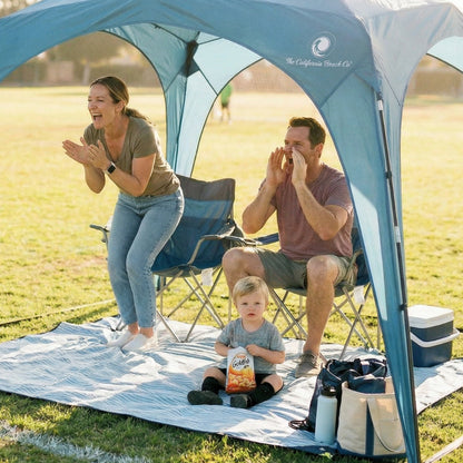 Pop 'N Go Canopy blue portable shade shelter with The California Beach Co. logo; family under canopy on grass on Tampa Home & Garden Store