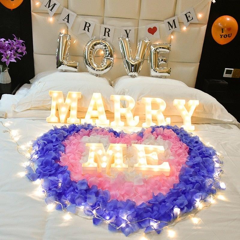 Artificial rose petals in pink and purple form a heart with LED lights and MARRY ME letters on Tampa Home & Garden Store