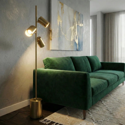 Harmony gold floor lamp with triple spotlights on a block base beside a gray wall and green sofa on Tampa Home & Garden Store
