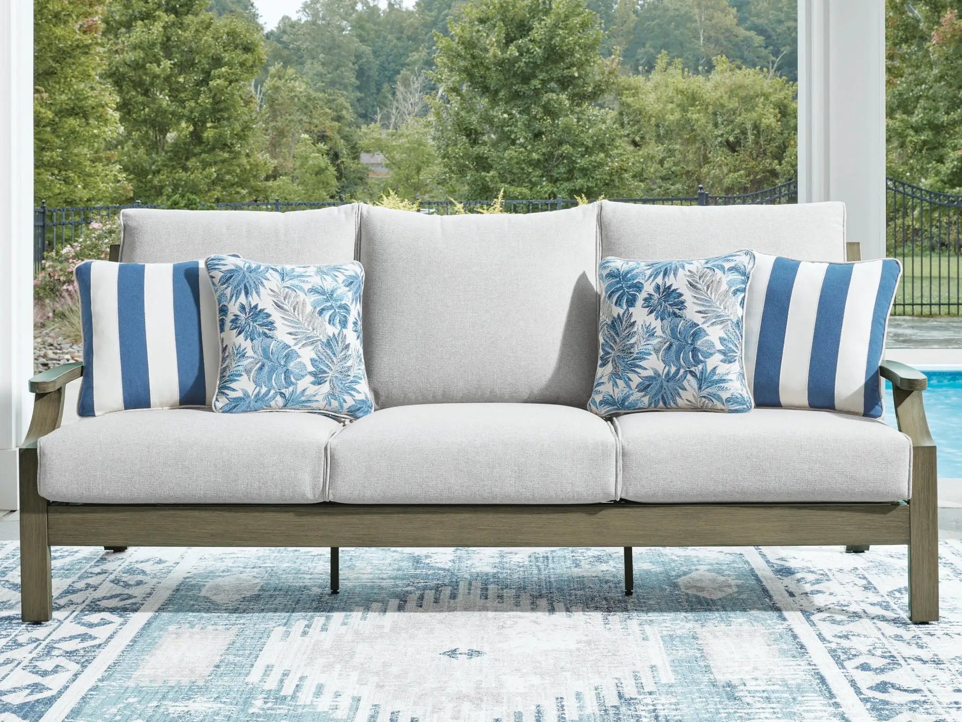 Rainier Ranch sofa with beige cushions; blue leaf-pattern and blue striped pillows on Tampa Home & Garden Store