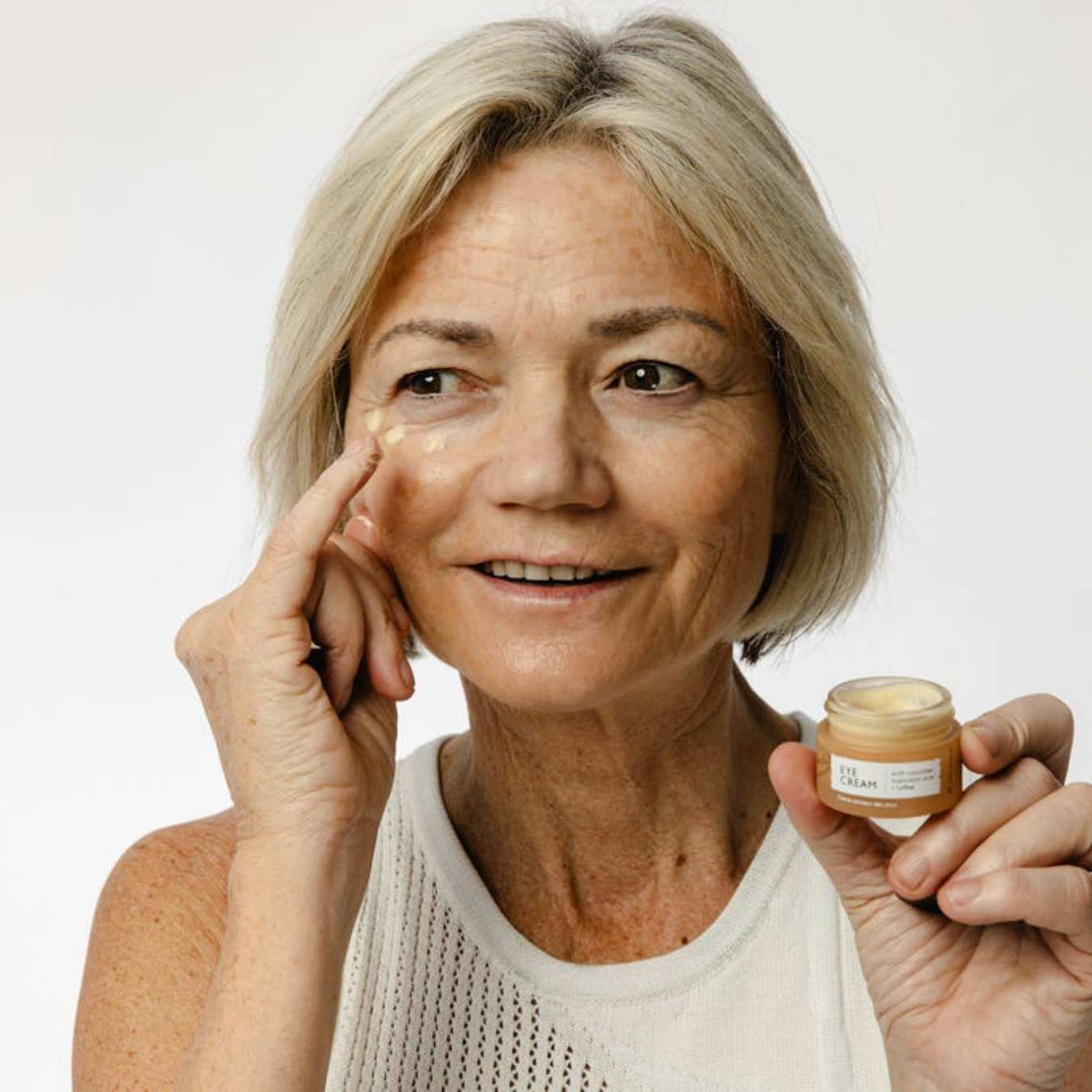 Eye Cream with Hyaluronic Acid & Coffee by UpCircle; woman applies beige jar cream under eye on Tampa Home & Garden Store