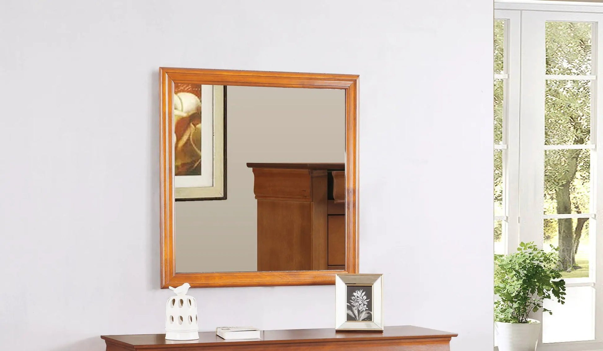 Traditional wall mirror with warm wood veneer frame on a light gray wall above a wooden console on Tampa Home & Garden Store