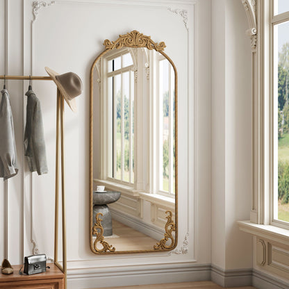 Full-body arched wall mirror with gold carved applique on a white paneled wall on Tampa Home & Garden Store