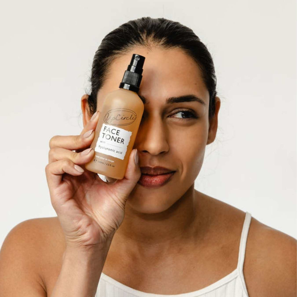Face Toner with Hyaluronic Acid spray bottle by UpCircle held beside model's face on Tampa Home & Garden Store