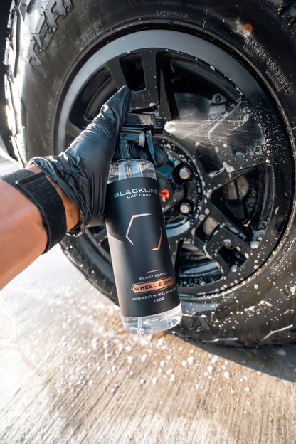 Blackline Car Care Wheel N' Tire Cleaner bottle sprayed on a black alloy wheel by a gloved hand on Tampa Home & Garden Store
