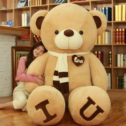 Heart Bear plush toy by FLIPSTYLEZLLC, oversized tan teddy wearing a cream scarf and love patch on Tampa Home & Garden Store