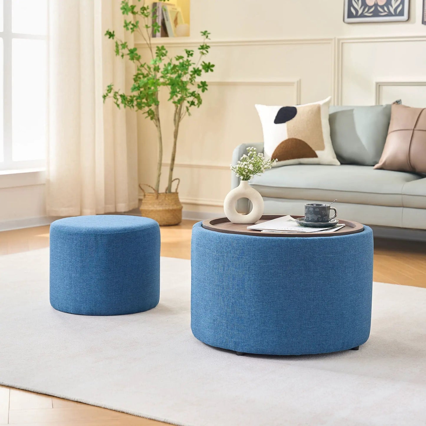 Two blue round ottomans beside a round wood coffee table in living room on Tampa Home & Garden Store