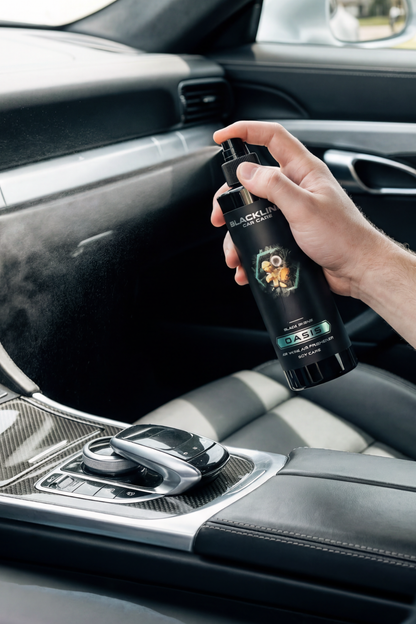 BLACKLINE 8oz Car Air Freshener spray bottle held in car, black bottle with Oasis label on Tampa Home & Garden Store