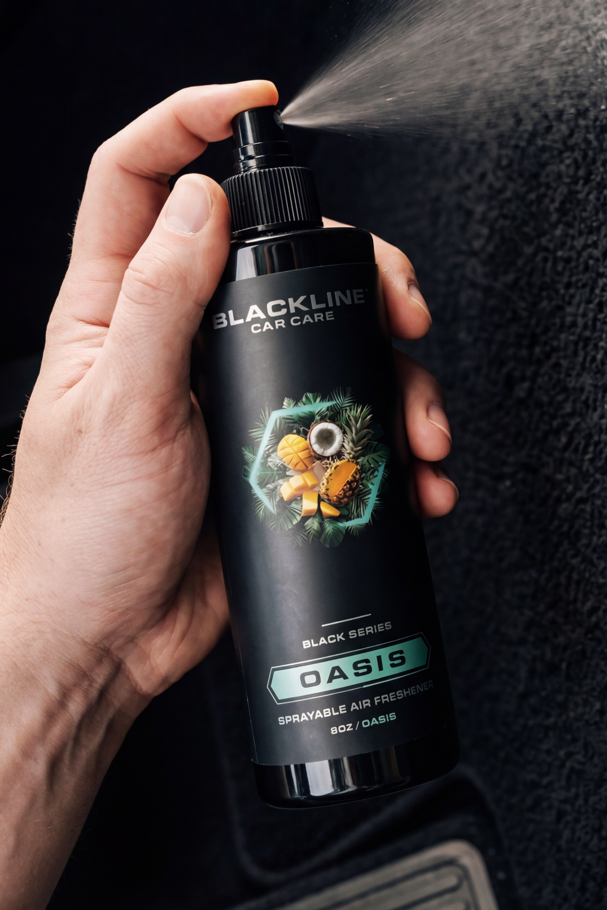 Blackline Car Care 8oz Oasis spray air freshener held in hand, spraying mist from the nozzle on Tampa Home & Garden Store