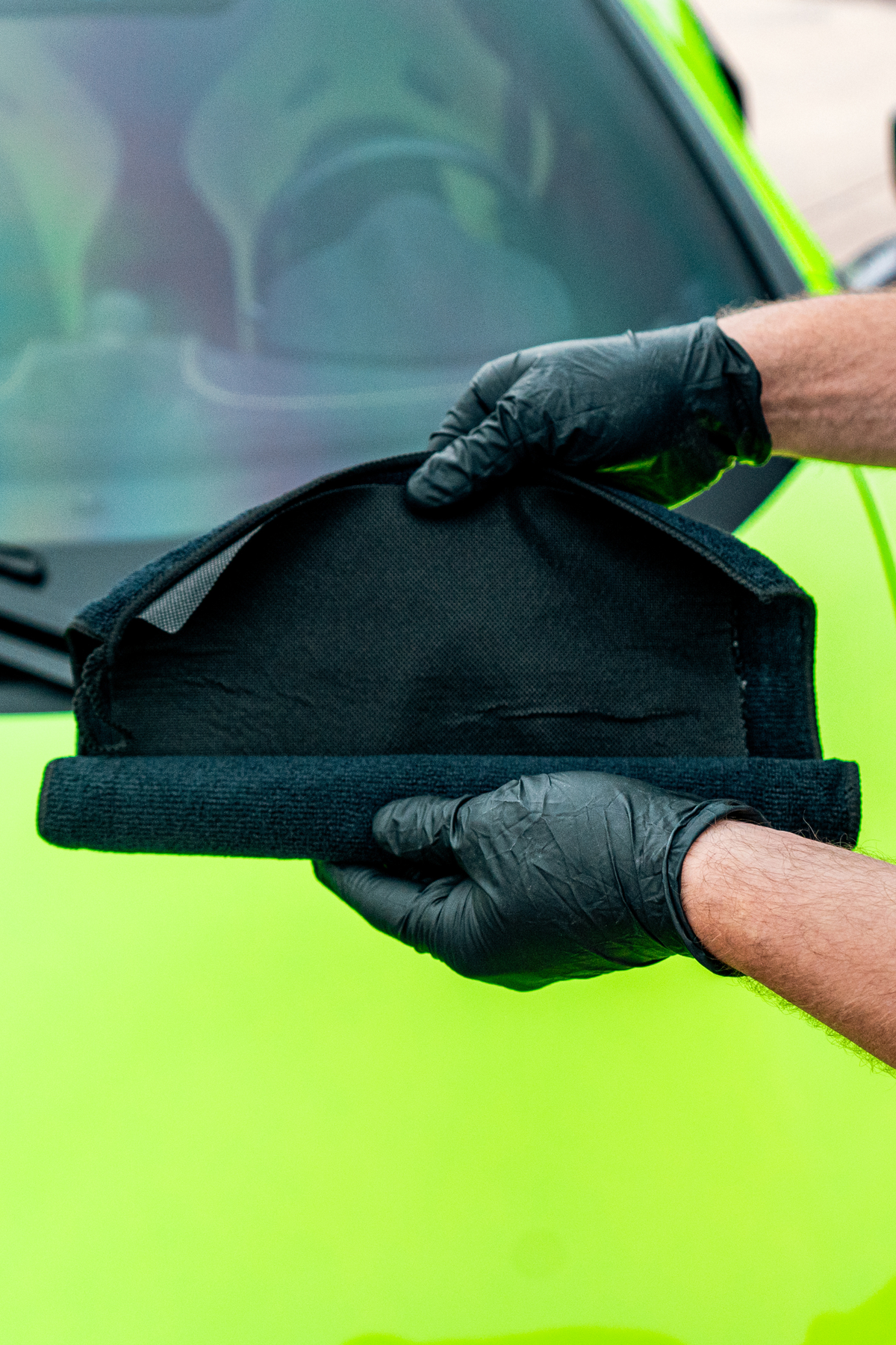 Blackline Synthetic Clay Towel black held by gloved hand against neon green car on Tampa Home & Garden Store