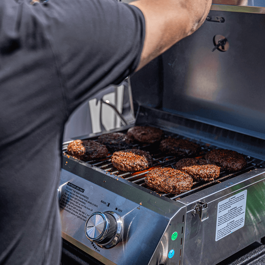 Tabletop propane gas grill 13742 by Monument Grills, stainless steel with 8 burger patties on Tampa Home & Garden Store