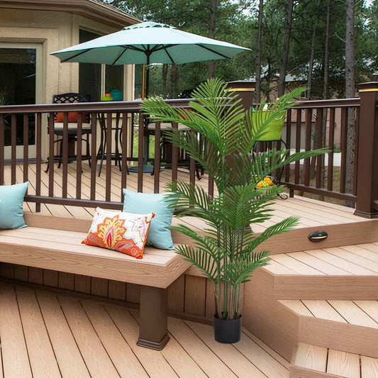 Artificial palm plant with plastic green leaves in a black pot on a wooden deck on Tampa Home & Garden Store