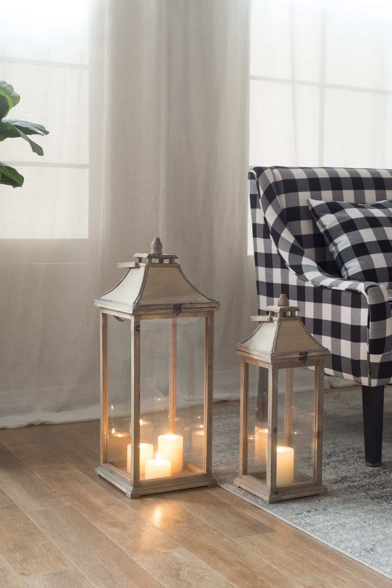 Candle lanterns, two ivory lanterns, wooden frames with glass panels and metal tops, lit candles on Tampa Home & Garden Store