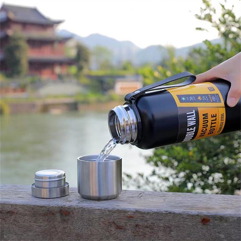 Stevvex 1500ml stainless thermos water bottle pouring into metal cup black with silver cap on Tampa Home & Garden Store