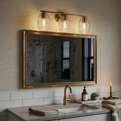Luster 3-light vanity wall lamp satin gold with clear glass shades above a bathroom mirror on Tampa Home & Garden Store