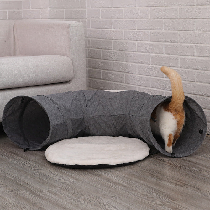Cat tunnel in gray fabric with a white plush cushion; orange cat entering from the end on Tampa Home & Garden Store