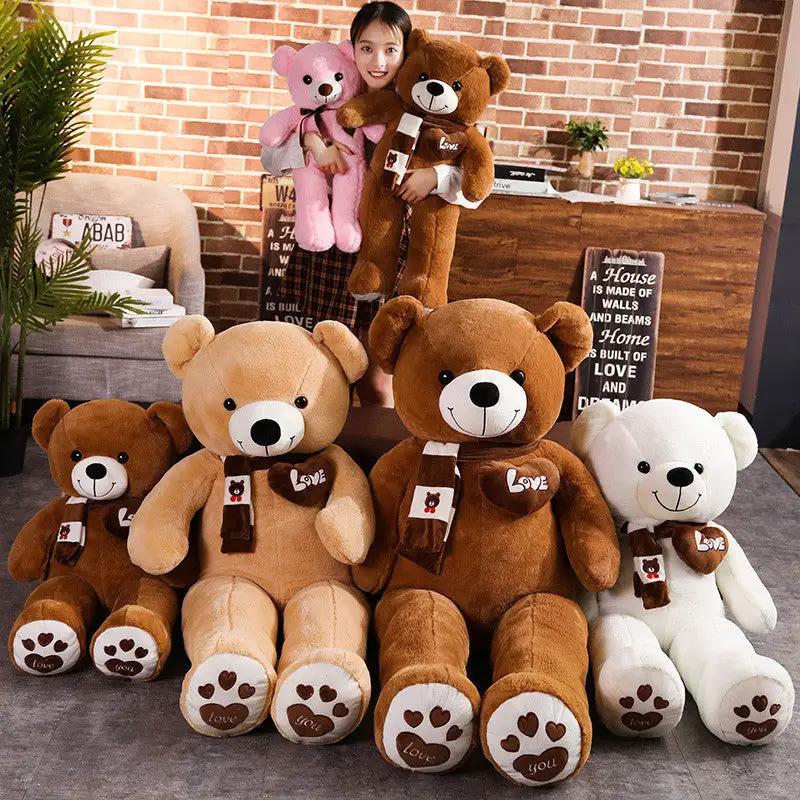 Six bear plush toys in brown, tan, white and pink with scarves; girl holds pink and brown bears on Tampa Home & Garden Store