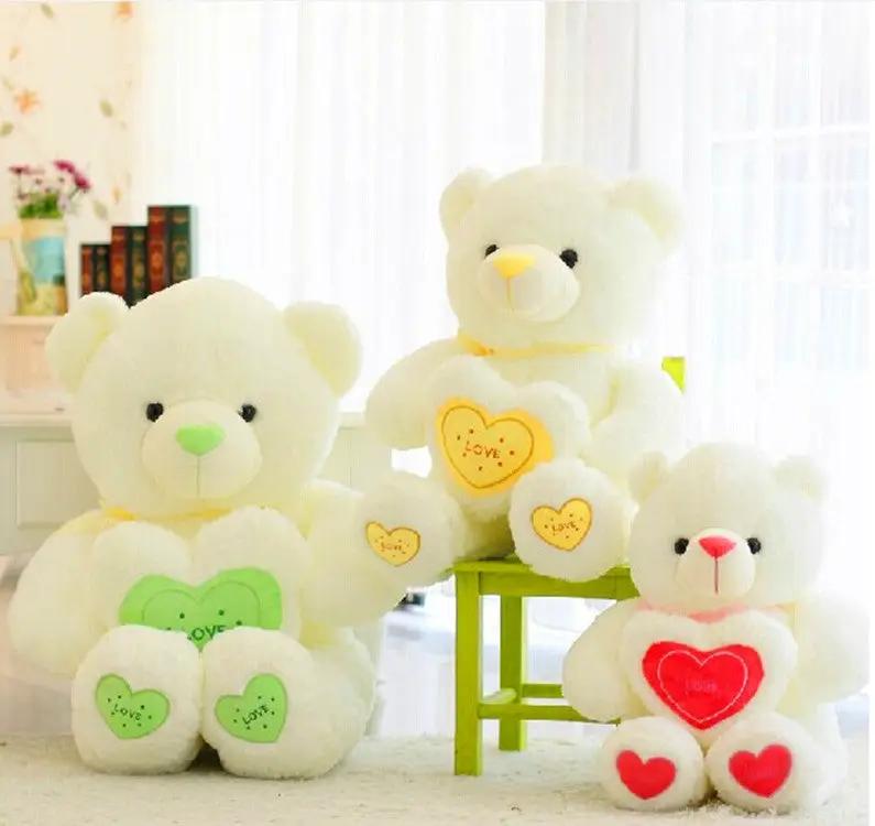 White hugging bear plush trio with green, yellow and red heart patches on chest and paws on Tampa Home & Garden Store