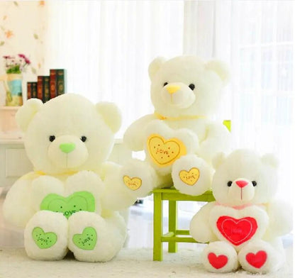 White hugging bear plush trio with green, yellow and red heart patches on chest and paws on Tampa Home & Garden Store