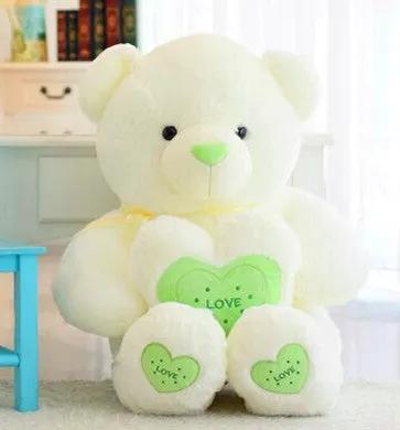 Cream hugging teddy bear plush with green heart patches reading LOVE on Tampa Home & Garden Store