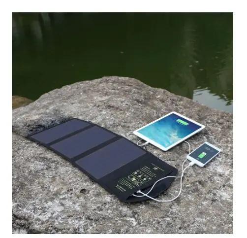 Foldable black solar charger with dual USB ports charging a tablet on a rocky lakeside on Tampa Home & Garden Store