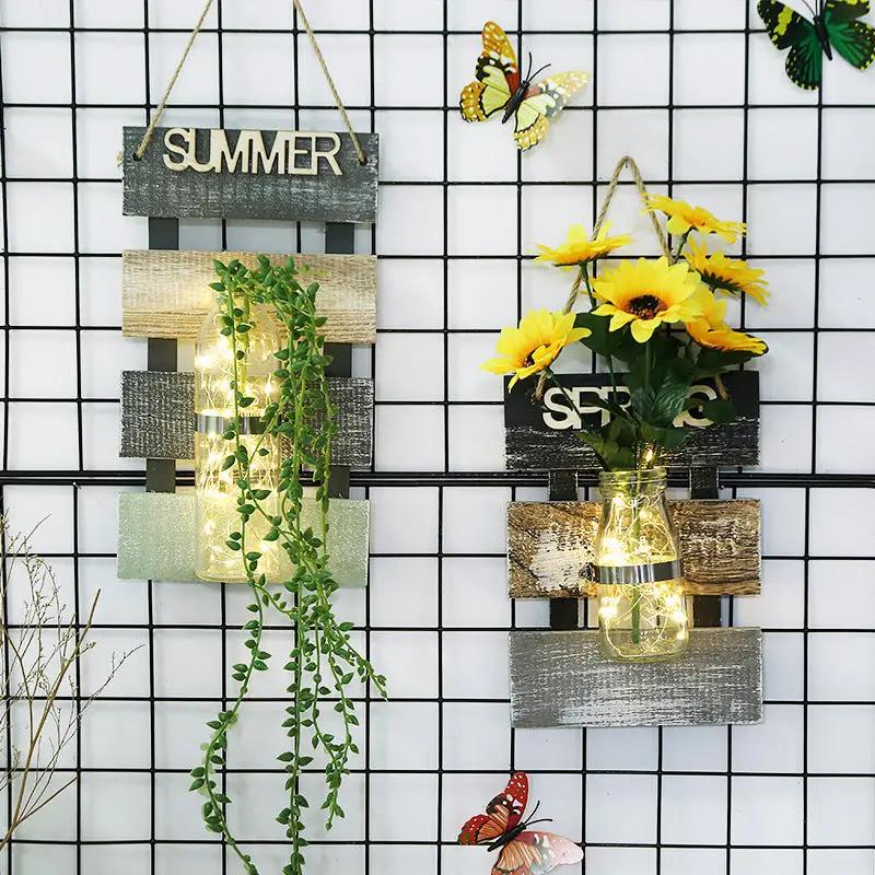 Glass plant vase wall hanging with rustic wood panels and string lights, greenery on Tampa Home & Garden Store