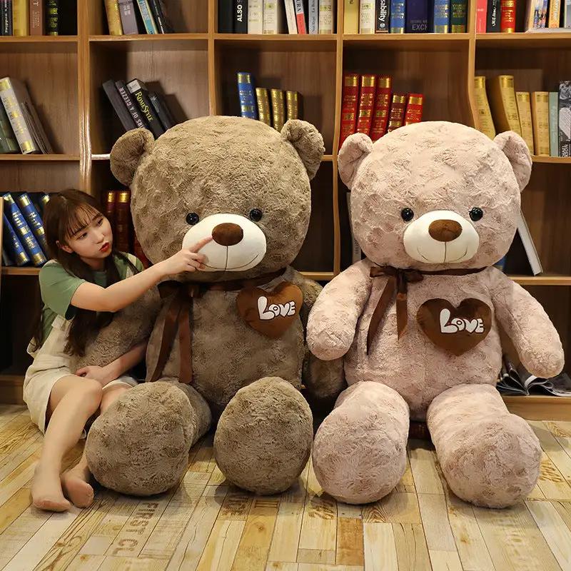 Two large teddy bears, brown and pink, with Love heart patches and ribbons by bookshelves on Tampa Home & Garden Store