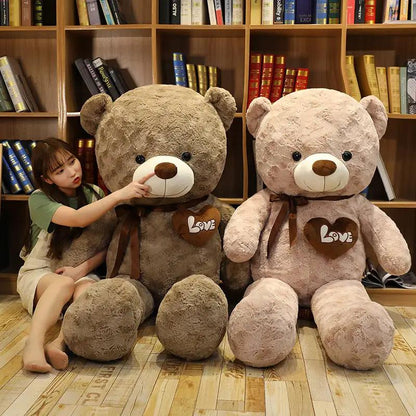 Two large teddy bears, brown and pink, with Love heart patches and ribbons by bookshelves on Tampa Home & Garden Store