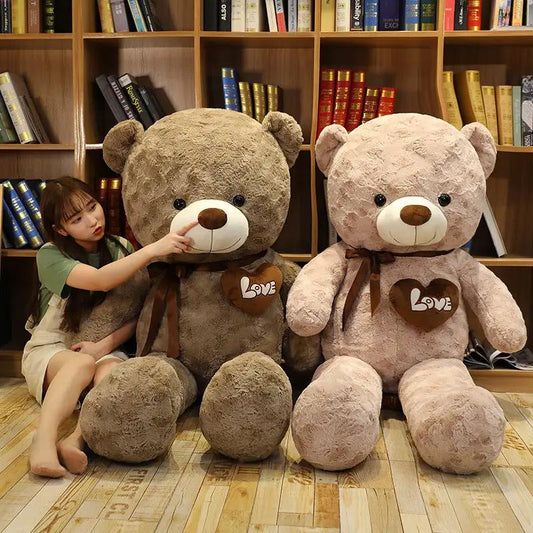 Two large teddy bears, brown and pink, with Love heart patches and ribbons by bookshelves on Tampa Home & Garden Store