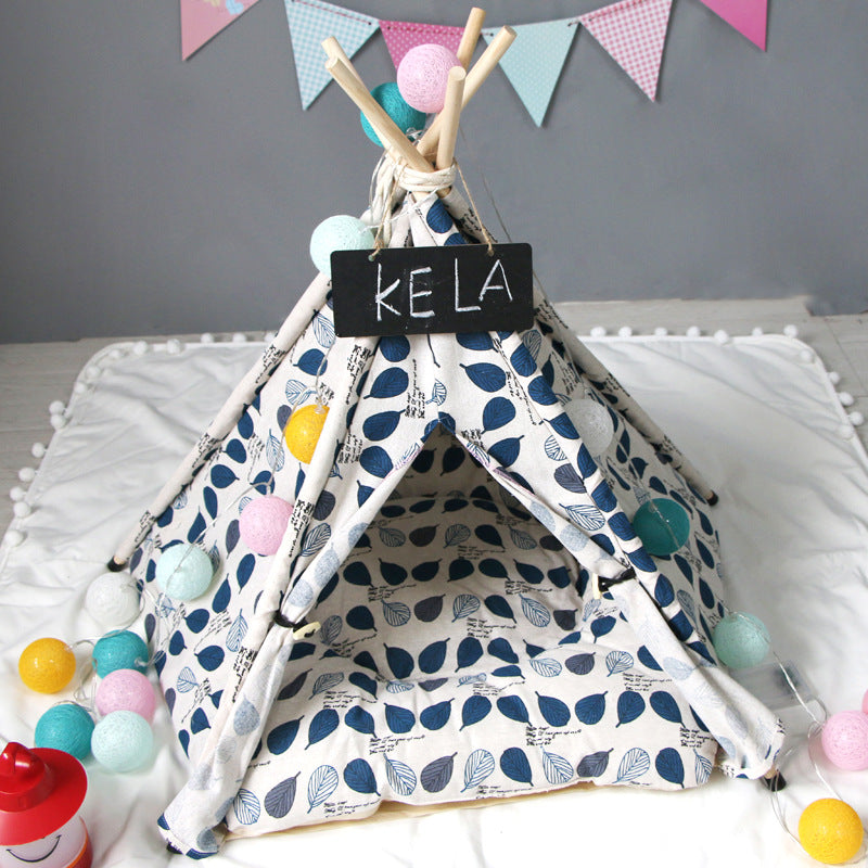 Dog kennel cat tent with blue leaf print fabric, wooden poles, and string lights, KELA sign on Tampa Home & Garden Store