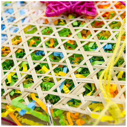 Bird brushed straw toy in a woven lattice basket with colorful shredded paper confetti and pink/yellow cords on Tampa Home & Garden Store