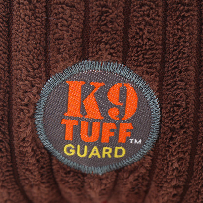 K9 TUFF GUARD patch on brown plush fabric with gray circular emblem and orange text on Tampa Home & Garden Store