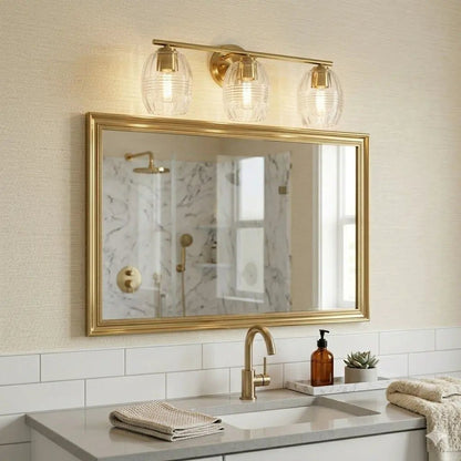 Luster 3-light vanity wall lamp with satin gold finish and clear glass shades above a mirror on Tampa Home & Garden Store