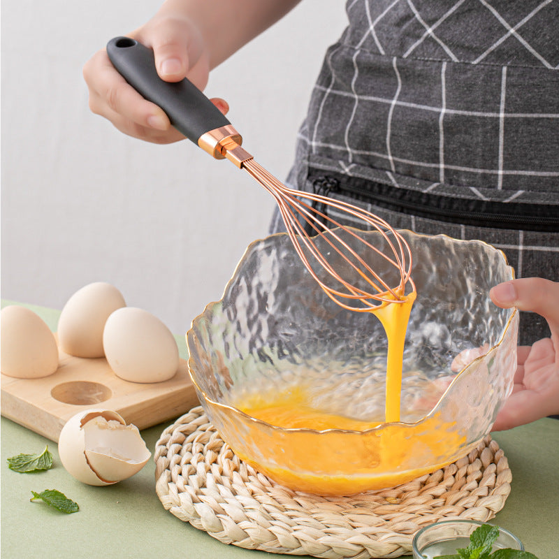 Perfecsy copper-plated kitchen whisk with copper wire tines, whisking eggs in glass bowl on Tampa Home & Garden Store